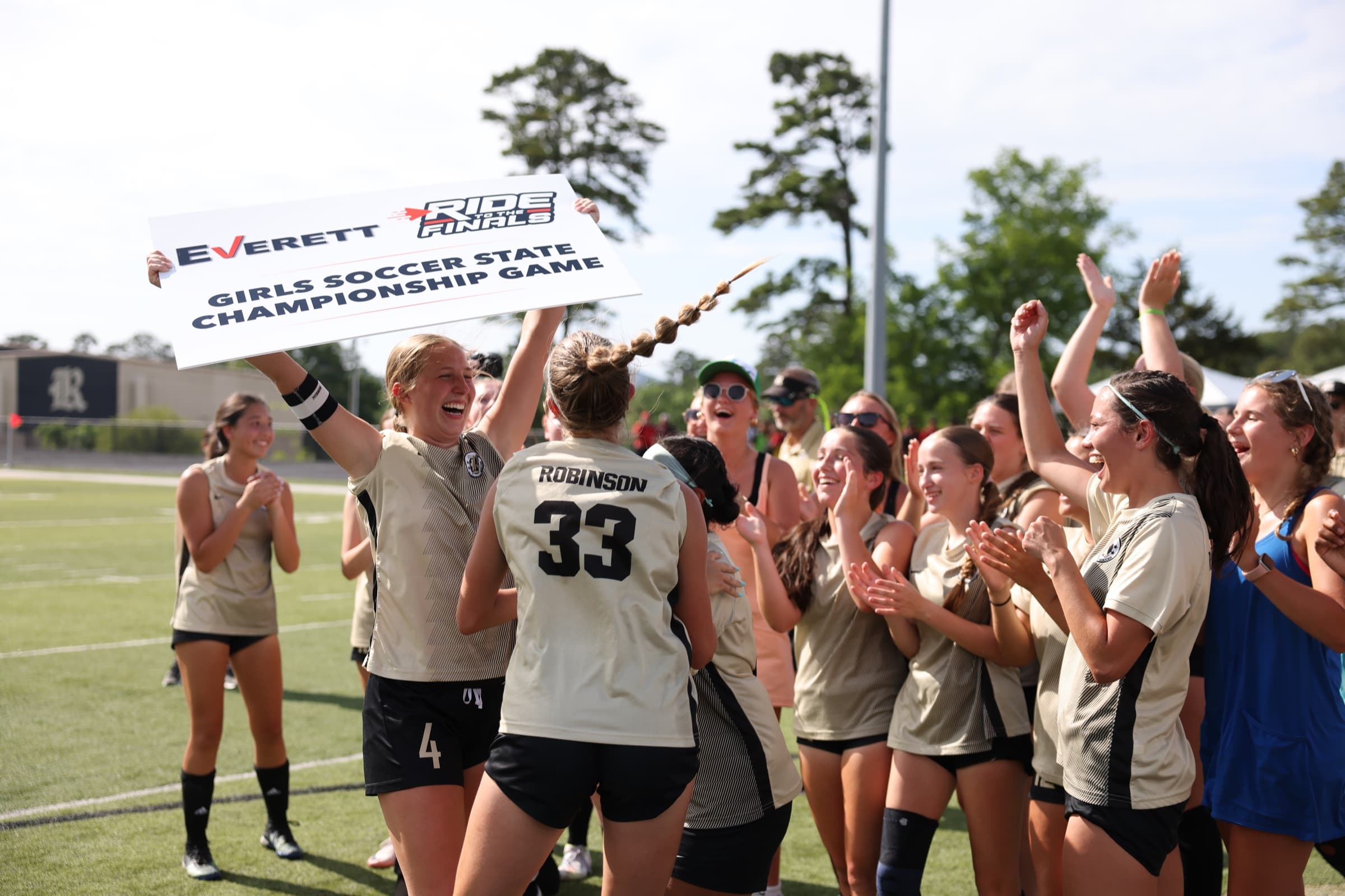 Girls soccer players celebrate together on the field after a championship game.